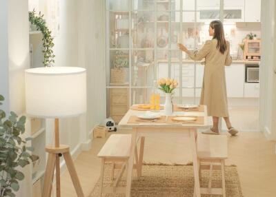 Bright dining area with a wooden table, benches, and a view into the modern kitchen