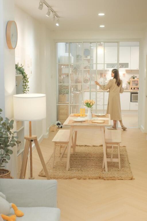 Bright dining area with a wooden table, benches, and a view into the modern kitchen