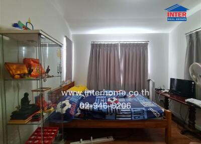 Bedroom with bed, display cabinet, and window with curtains