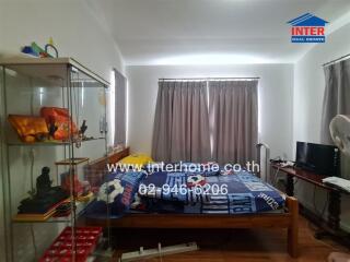 Bedroom with bed, display cabinet, and window with curtains