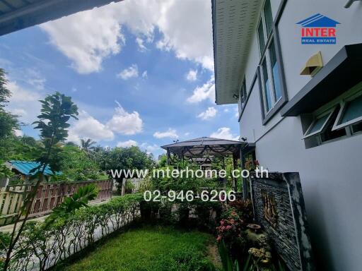 View of a garden area beside a house with a pathway, canopy, and greenery