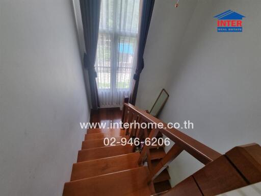 Wooden staircase with large window and blue curtains