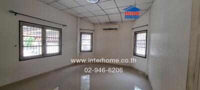 Empty room with tiled floor, large windows with security bars, air conditioning unit, and ceiling light