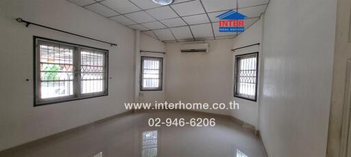 Empty room with tiled floor, large windows with security bars, air conditioning unit, and ceiling light