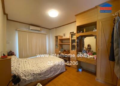 A cozy bedroom with a bed, wooden furniture, and a well-lit vanity area