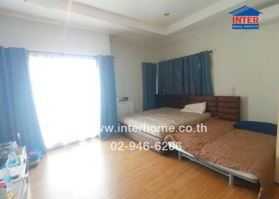 Spacious bedroom with two beds, large window with curtains, and wooden floor