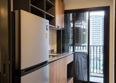 Compact modern kitchen with wooden cabinetry and stainless steel fridge