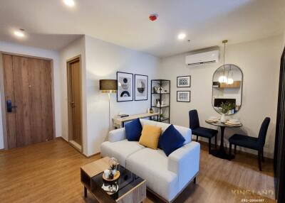 Living room with a sofa, dining area, and wooden flooring