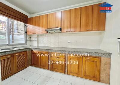 Modern kitchen with wooden cabinets, granite countertops, and tile flooring.