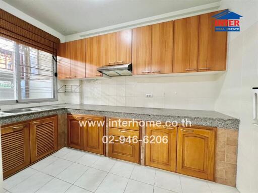 Modern kitchen with wooden cabinets, granite countertops, and tile flooring.