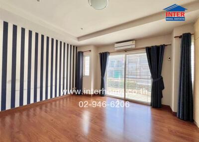 Spacious living room with striped accent wall and wooden flooring