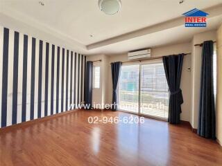 Spacious living room with striped accent wall and wooden flooring