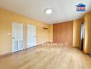 Spacious empty bedroom with wooden floors and yellow walls