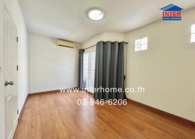 Empty bedroom with wooden flooring, gray curtains, and air conditioner