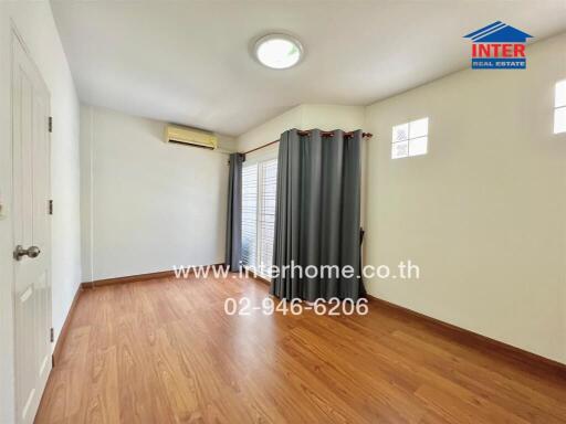 Empty bedroom with wooden flooring, gray curtains, and air conditioner