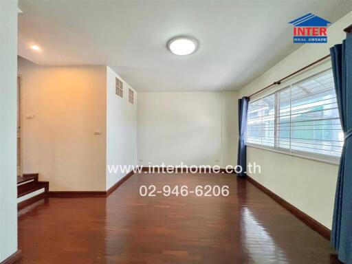 Bright and spacious living area with wooden flooring and large windows