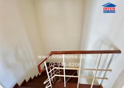 Staircase with wooden handrail and white walls