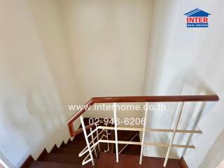 Staircase with wooden handrail and white walls