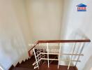 Staircase with wooden handrail and white walls