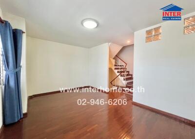 Spacious living area with wooden flooring and staircase