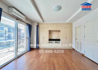 Spacious bedroom with wooden floor, built-in wardrobe, and large window