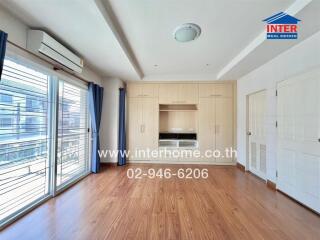 Spacious bedroom with wooden floor, built-in wardrobe, and large window