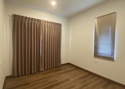 Empty bedroom with wooden floor, curtains, and blinds