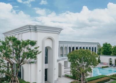 Exterior view of a luxurious white mansion with a pool and landscaped garden