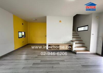 Spacious living room with yellow accent wall and staircase