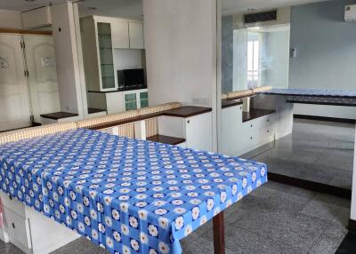 Dining area with a table covered with a blue patterned tablecloth, adjacent to a mirrored wall