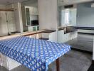 Dining area with a table covered with a blue patterned tablecloth, adjacent to a mirrored wall