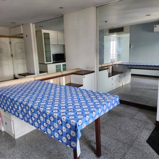 Dining area with a table covered with a blue patterned tablecloth, adjacent to a mirrored wall