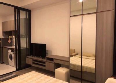 Modern bedroom with mirrored wardrobe and adjacent kitchen area