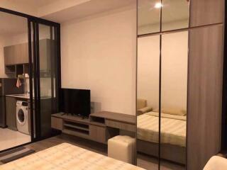 Modern bedroom with mirrored wardrobe and adjacent kitchen area