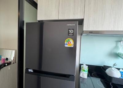 Modern kitchen with black fridge and light wood cabinets