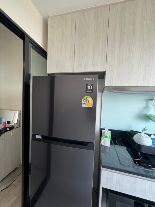 Modern kitchen with black fridge and light wood cabinets