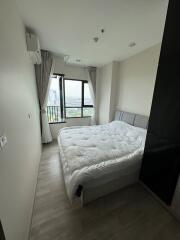 A modern bedroom with large windows offering city views.