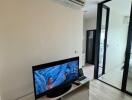 Living room with TV, air conditioning, and sliding glass door.