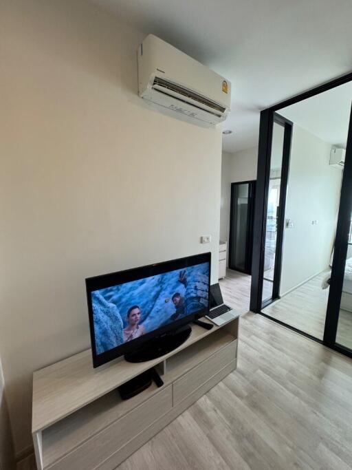 Living room with TV, air conditioning, and sliding glass door.