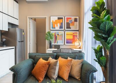 Modern living room with green sofa, plants, and artistic wall frames