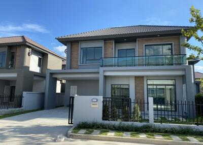 Modern two-story house with large windows and a fenced yard.