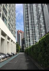 Tall apartment buildings with a driveway and parked cars