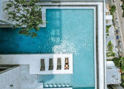 Aerial view of a swimming pool with a person sunbathing on a lounge chair