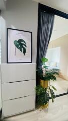 Bedroom with dresser, framed artwork, and potted plant next to sliding glass door