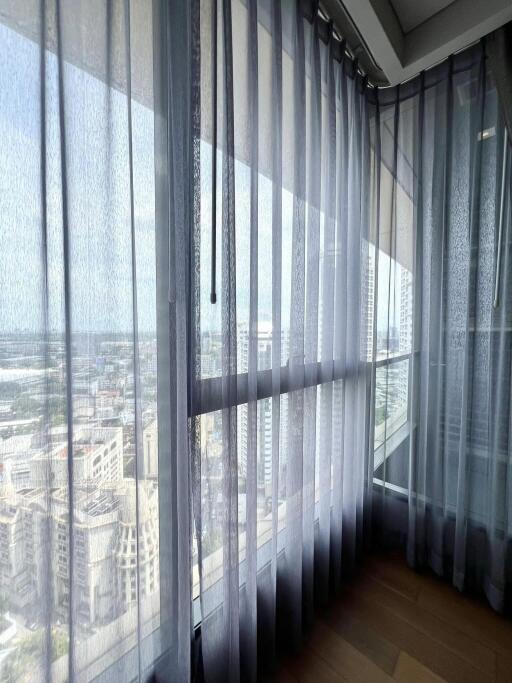 View of cityscape through large windows with sheer curtains