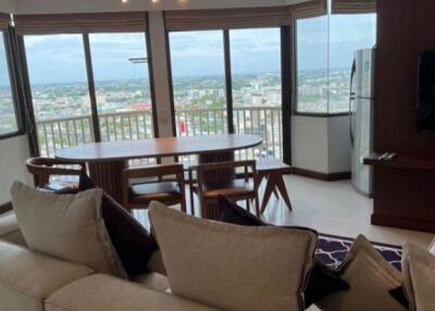 Spacious living room with large windows and panoramic city view, featuring a dining area and modern furnishings