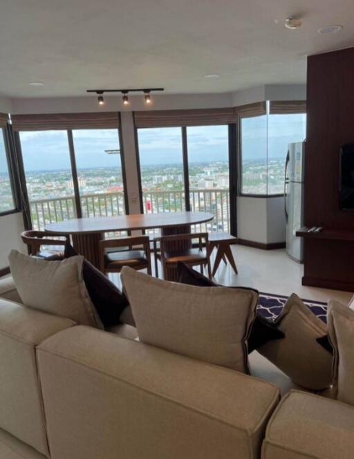 Spacious living room with large windows and panoramic city view, featuring a dining area and modern furnishings