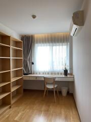 Bright, minimalistic bedroom with a wooden floor, large window, and workspace