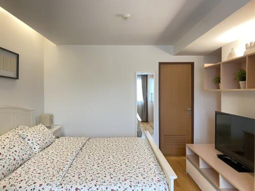 Modern bedroom with double bed, wooden door, and TV unit