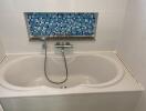 Bathroom with white bathtub and blue tile accent